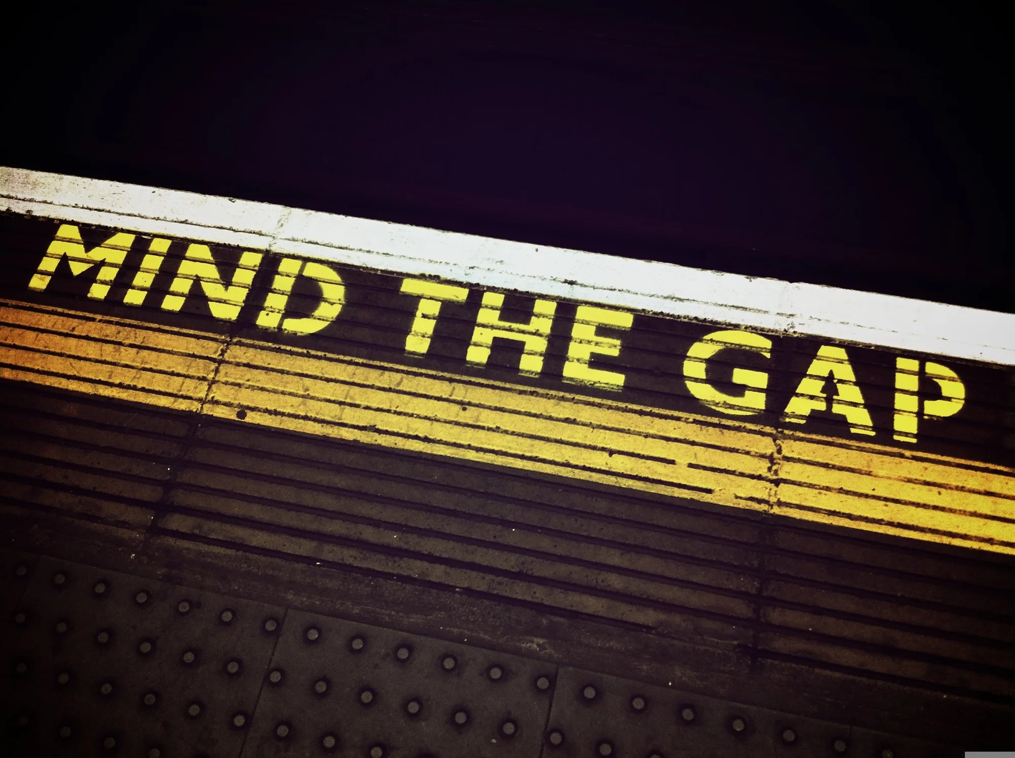 The words "Mind the Gap" painted in yellow at the edge of a train platform