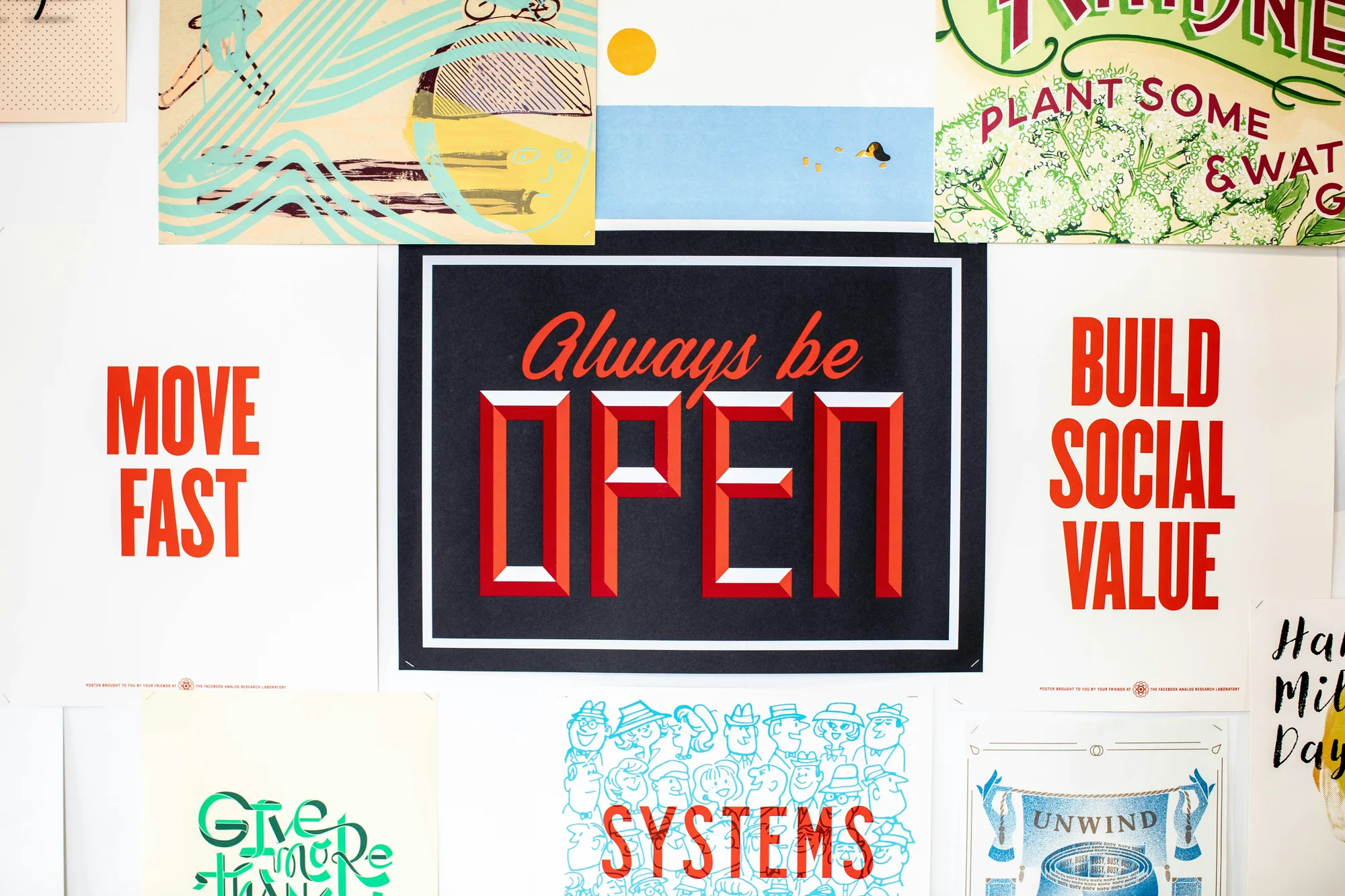 Wall of posters reading "Always be open", "Build social value", "Move fast" and "Systems"