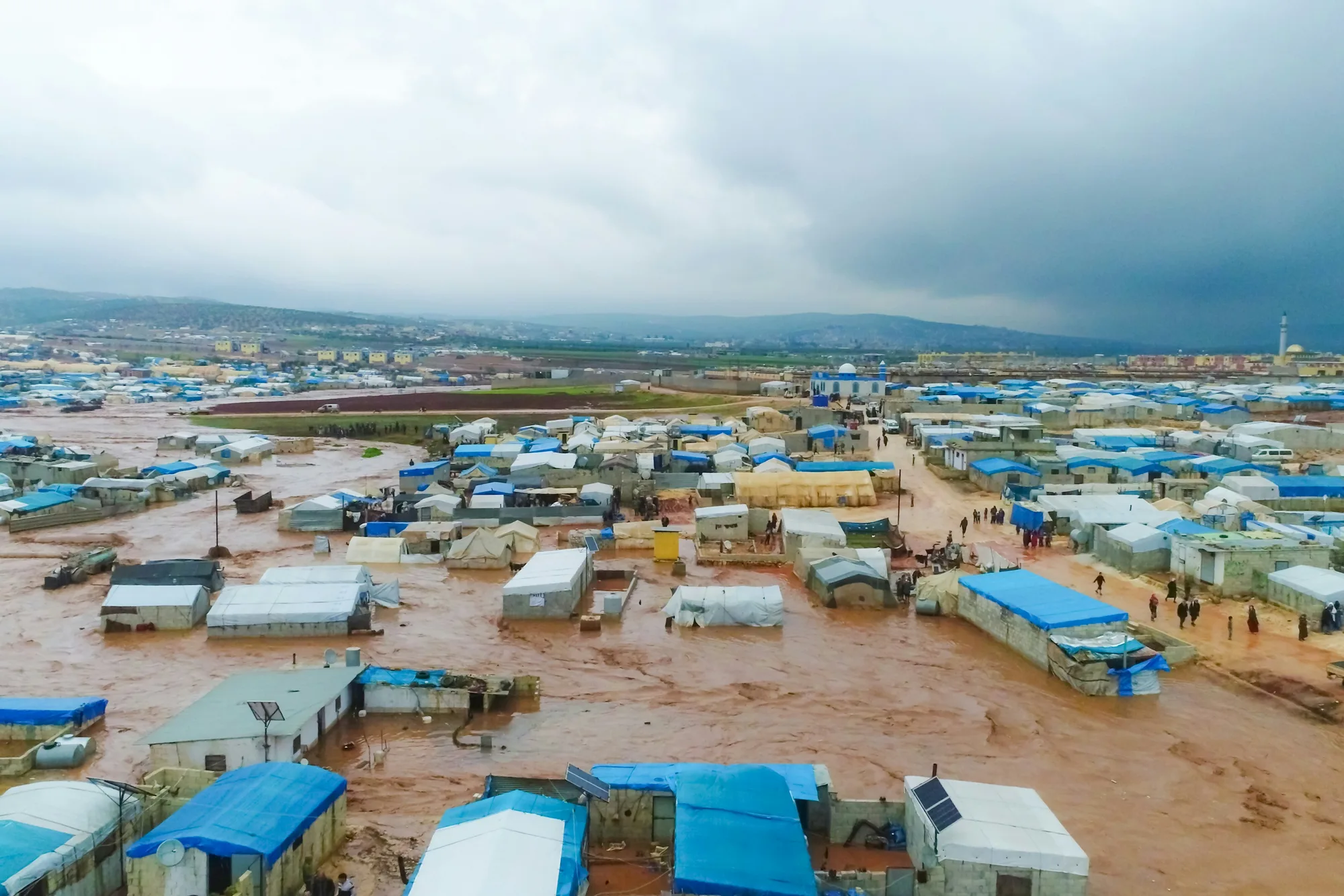 Aerial view of a muddy camp of temporary shelters after a disaster